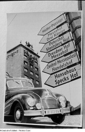 Vorderansicht eines fahrenden BMW 340, dahinter Wegweiser zu den Messehäusern, im Hintergrund das Kroch-Hochhaus (Fotomontage)
