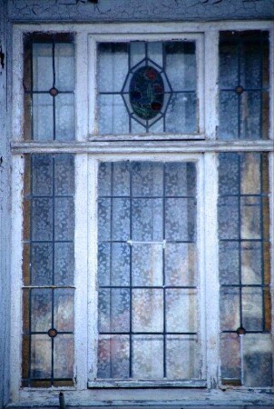 altes Fenster, bleiverglast, im Oberlicht ein Blumenmotiv