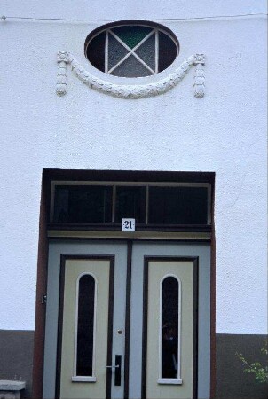 Hausdetail: zweiflügelige Tür, darüber liegendes Fensteroval mit Girlandenrelief