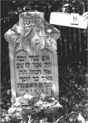 Grabstein 5 (Index: 100106683) Material: Sandstein Zustand: verwittert, Mittelaufsatz fehlt Maße HxBxT: 109x51x12 cm Beschreibung: Stele, Abschluß Sonderform, Mittelaufsatz fehlt, Schritfeld eingetieft in Maßwerkform, Sockel Symbolik: floral: Grabstein 5