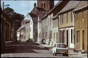 Lassan. Lange Straße mit parkendem PKW "Trabant". Blick zur Stadtpfarrkirche St. Johannis
