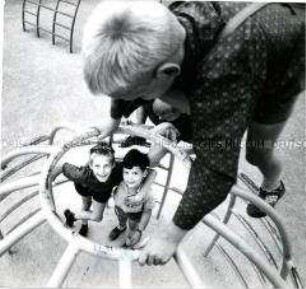 Aufsicht auf ein Klettergerüst an dem vier Jungen spielen, von denen zwei in die Kamera lachen