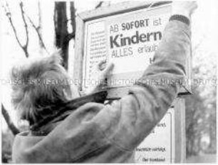 Junger Mann hängt ein Schild über ein Verbotsschild (Sonderthema: "Ich will ja nur dein Bestes." Eltern, Lehrer, Vorgesetzte)