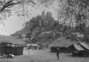 Lager : Das Lager der Expedition am Rande einer Siedlung. Im Hintergrund ein Kopje (Inselberg)