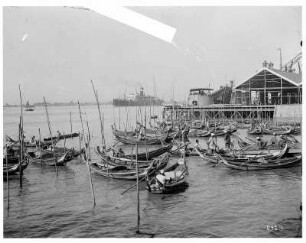 Rangun, Birma. Bootsanlegestelle im Hafen mit einheimischen Männern in Gondelkähnen, im Hintergrund Hochseepassagierdampfer der Hapag (evtl. Cleveland)