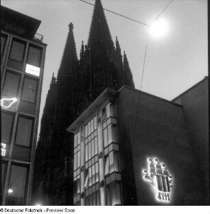 Köln. Architekturbild mit Türmen des Kölner Doms und Leuchtreklame für Kölnisch Wasser "4711"