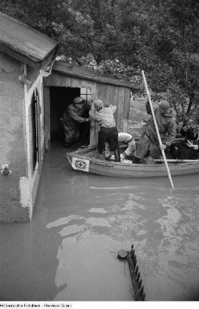 Männer in einem Rettungsboot an einem überschwemmten Haus
