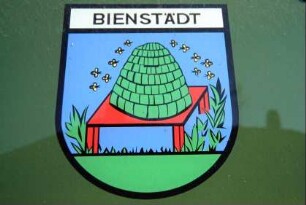 Tafel am Gemeindeamt mit Ortswappen; Tisch mit Bienenkorb