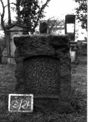 Grabstein 87 (Index: 99804728) Material: Granit Zustand: Platte fehlt Maße HxBxT: 90x60x22 cm Beschreibung: grob stelenförmig behauener Stein, eingetieftes Schriftfeld mit Segmentbogen: Grabstein 3/24