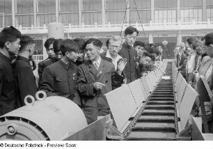 Besucher der Leipziger Herbstmesse 1954 wohnen der Vorführung eines Förderbandes der chinesischen Sektion bei