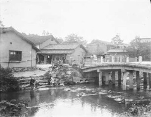 Siedlung : Frauen waschen ihre Wäsche im Fluss, rechts eine Steinbrücke