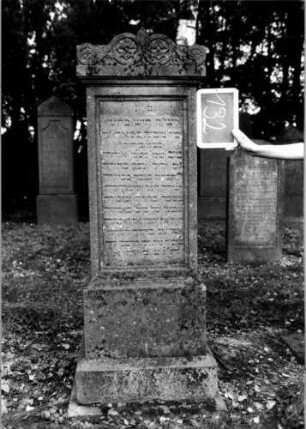 Grabstein 132 (Index: 100111270) Material: Sandstein Zustand: gut Maße HxBxT: 160x54x54 cm Beschreibung: Stele, getreppter Sockel, Abdeckplatte mit Volutenaufsatz, rechteckige Schriftfelder eingetieft Symbolik: Blüten, Voluten Besonderheit: kulturhistorisch wertvoll / hist.-wiss. Gründe: Grabstein 132