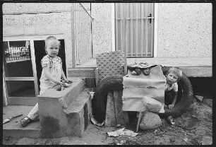 Zwei Jungen spielen im Sperrmüll vorr einem Plattenbau