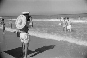 Eforie. Ein Mann fotografiert zwei andere Männer, die im Wasser stehen, am Strand am Schwarzen Meer