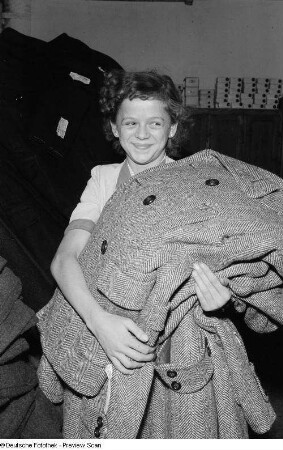 Portrait einer jungen Frau beim Transportieren von Trenchcoats im VEB Bekleidungswerk Leipzig