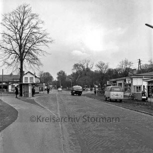 Möllner Landstraße: Kopfsteinpflaster: darauf Tanklaster und Pkw: rechts VW-Bus: dahinter Ladenzeile: hinten rechts Abzweigung der Bahnhofstraße: links Bushaltestelle mit Personen: daneben Baum: dahinter Wohnhäuser