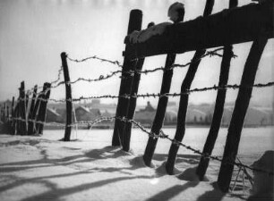 Winterbilder. Reste eines Holzzaunes mit Stacheldraht im Schnee