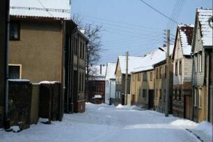 Dorfstraße mit dicht stehenden, vorwiegend giebelständigen Häusern, Winter