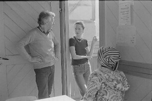 Höfgen. Akt-Pleinair 1979. Die Fotografen Günter Rössler und Eva Mahn im Gespräch, am Tisch sitzend ein Fotomodell mit Turban