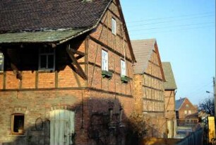 Bauernhäuser und Wirtschaftsgebäude, überwiegend rote Ziegel, vorn langes Schleppdach