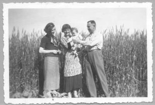 Gruppenbild im Freien mit junger Frau und Kleinkind (wahrscheinlich ein Familienbildnis)