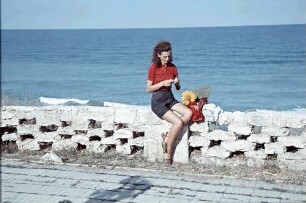 Eforie: Schwarzmeer Strand, Margarete Klein sitzt auf Steinzaun, Hintergrund Meer