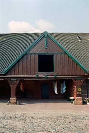 Fritz-Berodt-Straße 7-9: Hofanlage: Haus Nr. 7 [Haus am Teich]: Traufseite zum Hof, Teilansicht: ehemalige Remise mit Holzständern, darüber Frontispiz mit Verbretterung, Luke, oben Giebelzier: 21. Oktober 1993