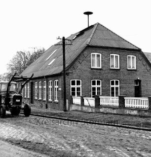 Schlamersdorf: Dorfstraße mit Kopfsteinpflaster: Volksschule: davor Strommast: rechts Zaun: vorn links Trecker