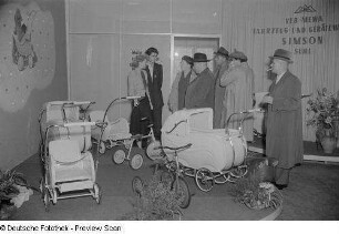 Besucher an einem Messestand mit Kinderwagen