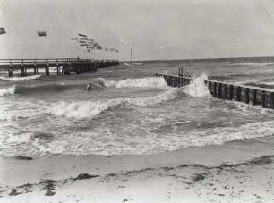 Heiligendamm, Seebrücke mit Flaggen und Wellenbrecher in der Ostsee. Blick vom Strand