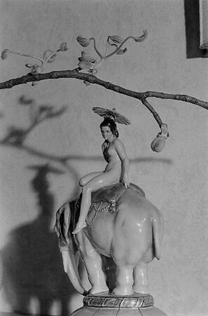 Porzellanfigur. Eine nackte Frau mit Schirm auf einem Elefanten reitend