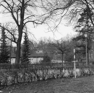 Kurpark: vorn Weg mit Hecken und Bäumen: hinten rechts Baracke: hinten rechts Gebäude
