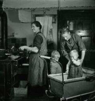 Arbeitsmaid des Reichsarbeitsdienstes bei der Kinderbetreuung in der Bauernküche