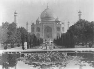 Einheimischer und Gruppe von Touristen posieren am Wasserbecken vor dem Taj Mahal : Weltreisen. Agra. Einheimischer und Gruppe von Touristen posieren am Wasserbecken vor dem Taj Mahal (1631-1648; U. A. Lahori, A. Fazel)