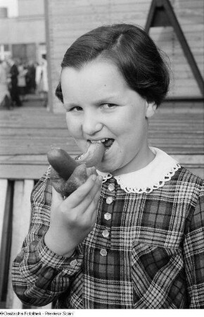 Mädchen mit Bockwurst im Brötchen auf der Kleinmesse am Cottaweg
