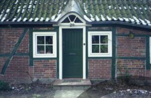 Kruthorst 29: Fachwerkhaus: traufständige Straßenfront: Detailaufnahme: Eingangstür, darüber Fledermausgaube, beiderseits Fenster, Hausnummer