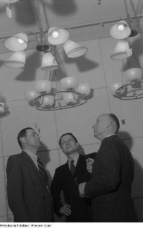 Besucher an einem Messestand mit Deckenlampen