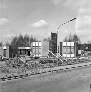 Lottbek: An der Lottbek: Evangelisch-lutherische Kirchengemeinde Hoisbüttel: Gemeindezentrum: Rohbau: davor Bauschild, Erd- und Sandhaufen sowie Baumaterial, Straßenlampe und Bauzaun: hinten Bäume und rechts Einfamilienhaus
