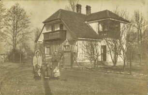 [Frauen mit Kindern vor alleinstehendem Haus]