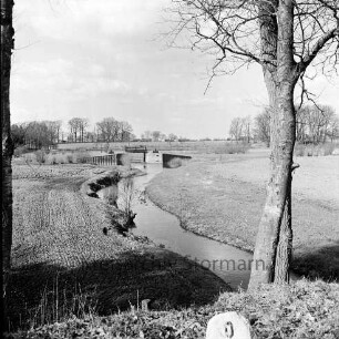 Alster: vorn rechts an Böschung Baum: rechts und links angrenzende Felder: hinten Mitte Sandfelder Schleuse. dahinter Bäume