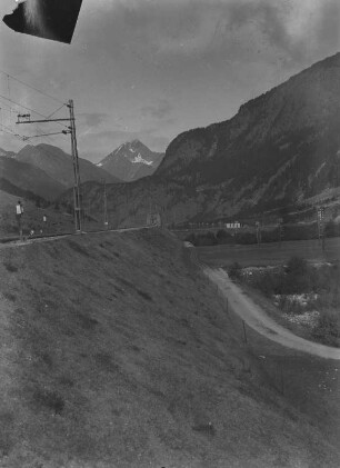 Piz Linard : Blick über die Straße und zwischen die Berge auf den Piz Linard, der mit Schnee bedeckt ist.