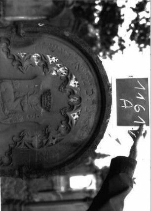 Grabstein 1161 (Index: 100104286) Material: Sandstein Zustand: gut erhalten, nur im Bogenbereich leicht verwittert Maße HxBxT: 170x70x18 cm Beschreibung: Stele mit Rundbogenabschluss, Verdachung, Schriftfeld eingetieft, im Bogenfeld Maßwerk (Rundbogenfries), darunter aufgesetztes Wappen mit Hirsch, drei Laubbäumen und Krone Symbolik: Wappen, Hirsch, drei Laubbäume, Krone, Rundbogenfries: Grabstein 1161A