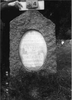 Grabstein 34 (Index: 99792487) Material: Granit, weiße Marmorplatte Zustand: gut Maße HxBxT: 142x60x26 cm Beschreibung: Stele, giebelartiger Abschluß, ovale Schriftplatte: Grabstein 34