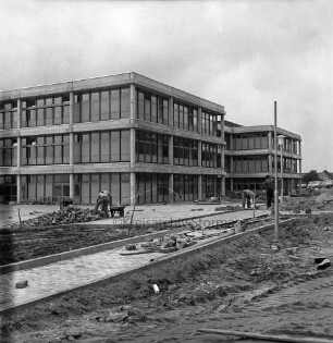 Schulzentrum mit Hauptschule, Realschule und Gymnasium [später Gemeinschaftsschule Sönke-Nissen-Schule und Gymnasium Glinde]: Oher Weg: Neubau vor Fertigstellung: vorn Arbeiter beim Verlegen der Gehwegplatten und Errichten der Außenanlagen