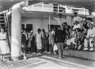 Freizeitgestaltung : Personen auf einer Tribüne auf dem Zwischendeck eines Schiffes, vor ihnen Frauen beim Spiel