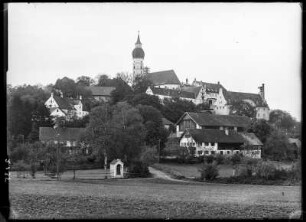 Andechs. Stadtteilansicht mit Wohnhäusern und Blick zur spätgotischen Klosterkirche