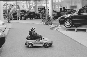 Junge im Kinderauto eines Autohauses