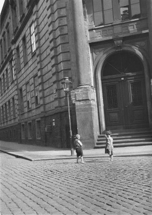 Kinder auf der Straße vor dem Eingang zu einem Verwaltungsgebäude (?)