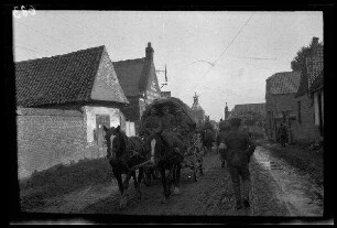 Metz-en-Couture (Dep. Pas-de-Calais, Frankreich): Pferdegespanne mit Planwagen auf einer morastigen Ortsstraße, im Hintergrund die Kirche