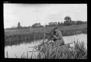 Bei Douai (Dep. Nord, Frankreich): Offiziersaspirant mit Schirmmütze und Soldat mit Pickelhaube und Gewehr auf einem provisorischen Floß im Wasser "am Kanal"